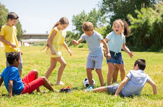 Un grupo de niños juega al fútbol en la hierba.