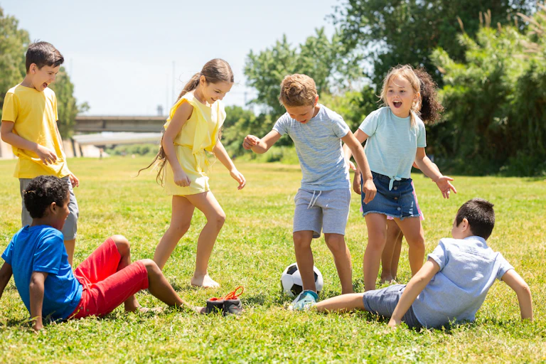 Un grupo de niños juega al fútbol en la hierba.