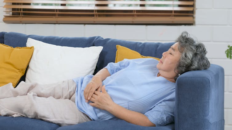 An elderly woman naps on a couch.