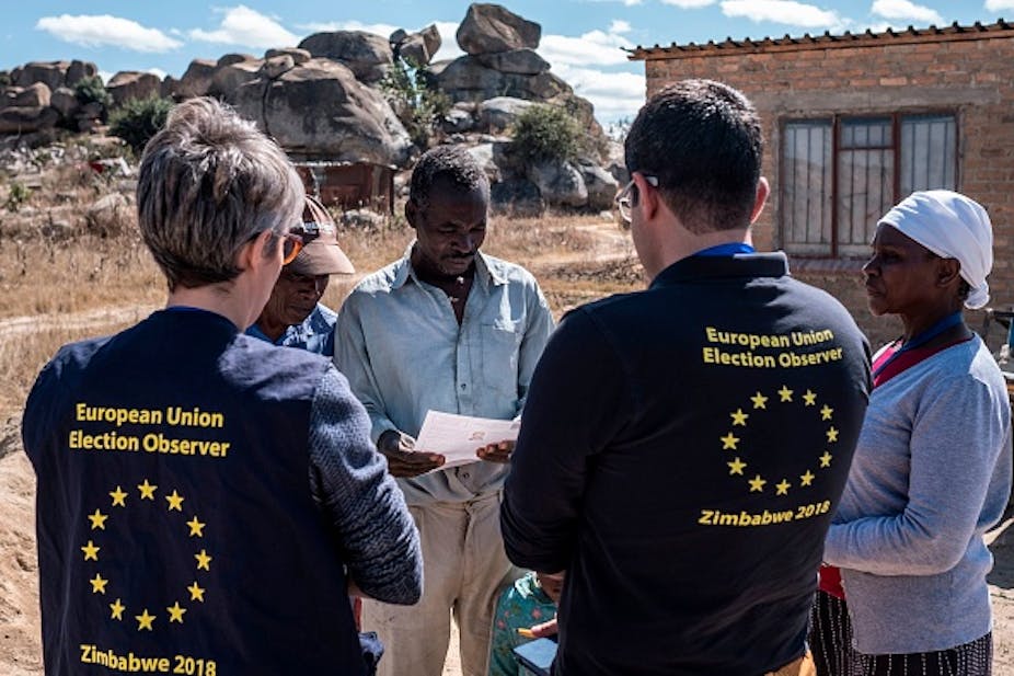 Two EU election observers speak to three villagers in Zimbabwe.