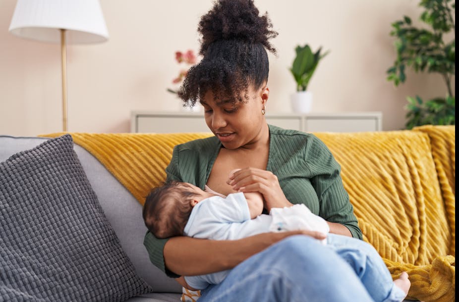A woman breastfeeding a baby while sitting on a sofa