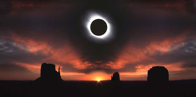 A total solar eclipse, where the sun is eclipsed by the Moon, leaving only shadowy light visible from behind the Moon's silhouette. Below, there is a sunset over Moab, Utah with rock plateaus and formations visible. 