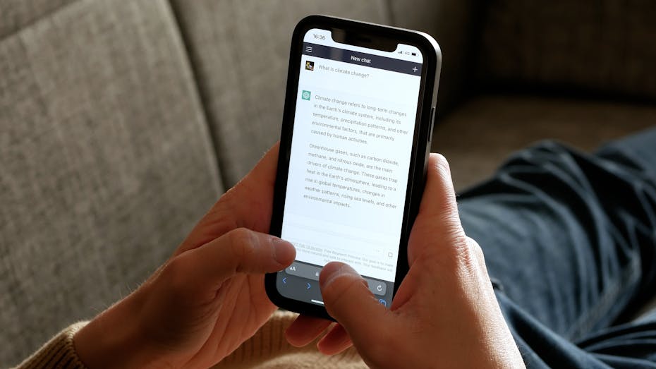 A pair of hands hold a cellphone displaying a virtual conversation with a chatbot