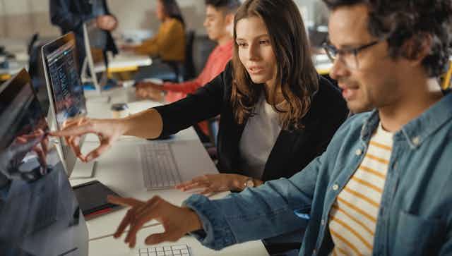 Man and woman pointing at computer screen