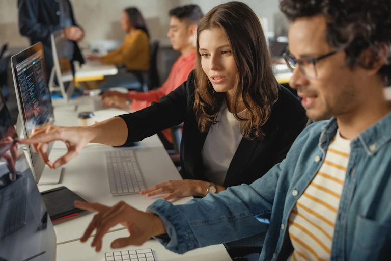 Man and woman pointing at computer screen