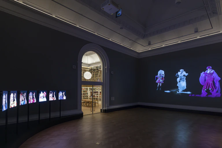 A darkened gallery showing a colourful photography exhibition.