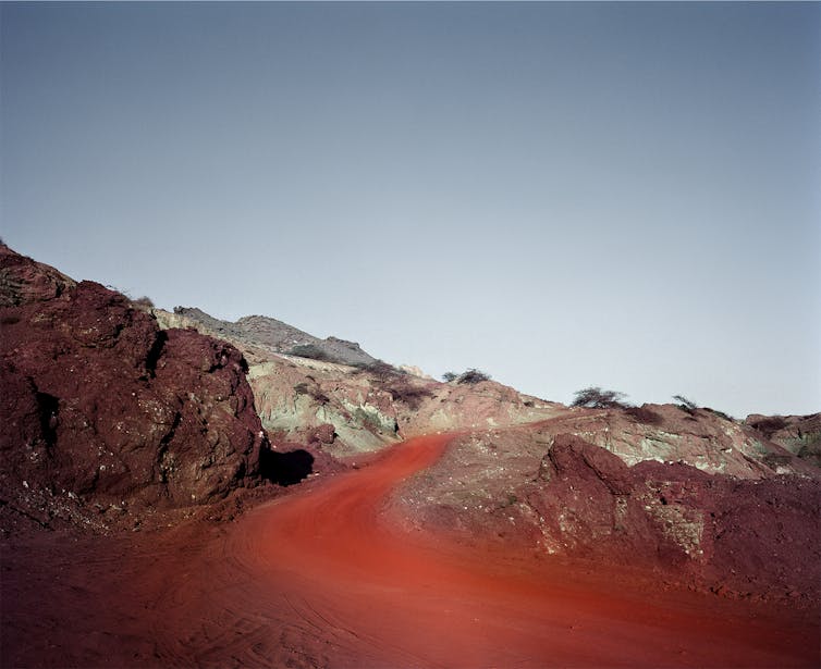 A desert scene with copper-red sand and dusty landscape.