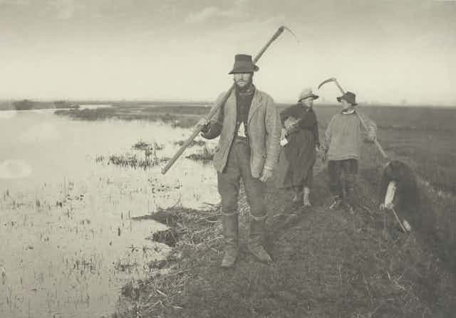 1886 black and white photo of three country people by a marsh with tools