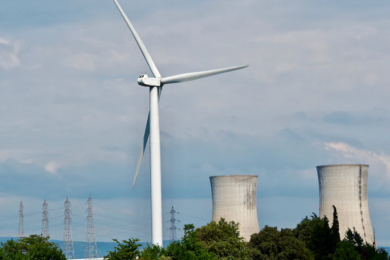 paysage avec une éolienne à l'avant et une centrale nucléaire à l'arrière