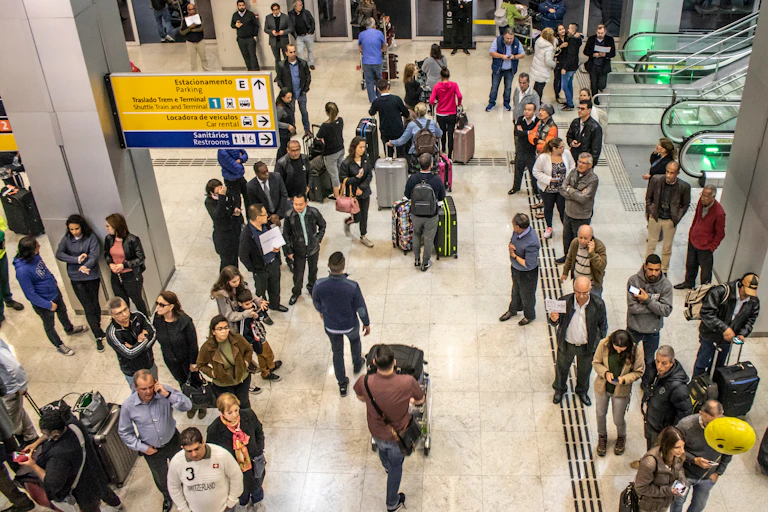 Overhead shot of travellers and others walking around and waiting in an airport arrivals hall