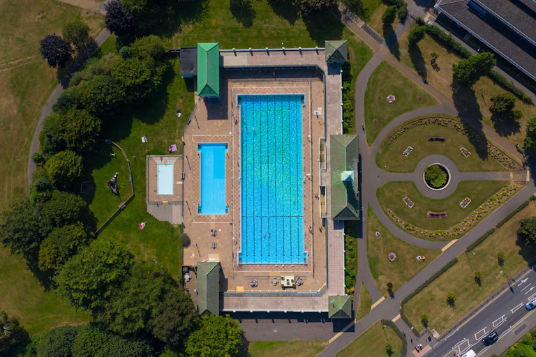 Peterborough's Vivacity Lido in an aerial shot showing its blue water and surrounding greenery.
