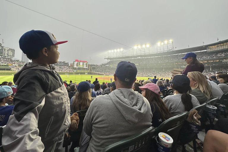 A young boy stands up among fans watching the Phillies-Cubs game. Smoke is evident in the air.