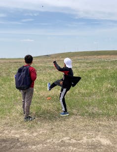 Two young boys throwing seeds in a feild.