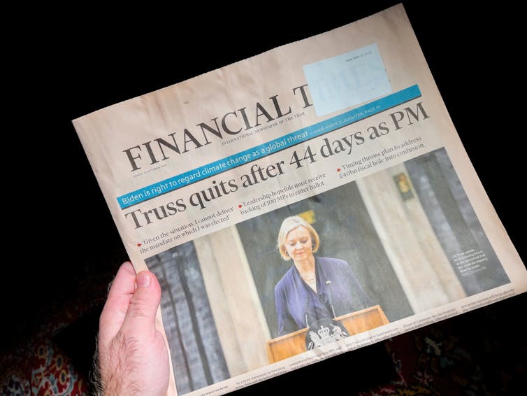 Hand holding a copy of the Financial Times newspaper with image of Liz Truss and headline: 