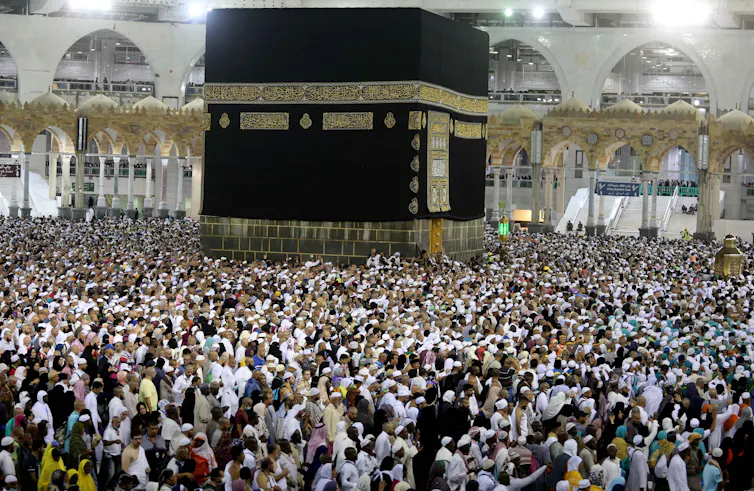 A large number of people gathered around a black structure, the Kaaba.