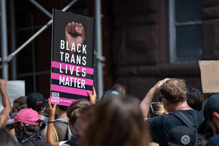 Un manifestante sostiene un cartel que apoya a los transexuales negros.