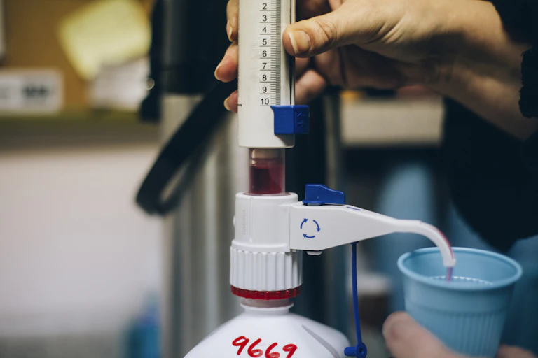 Photo of a hand dispensing a measured dose of red liquid.