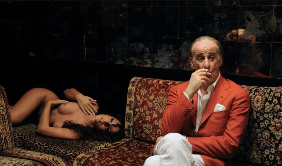 Un homme élégant fume sur un divan, une femme nue couchée près de lui.