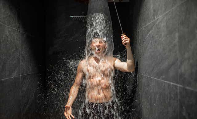Un joven tomando una ducha visiblemente fresco.