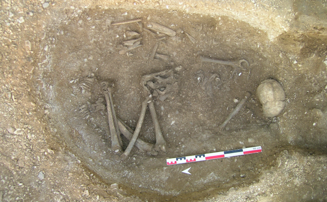 A grave with skeletal remains of a person with skull and long bones clearly visible