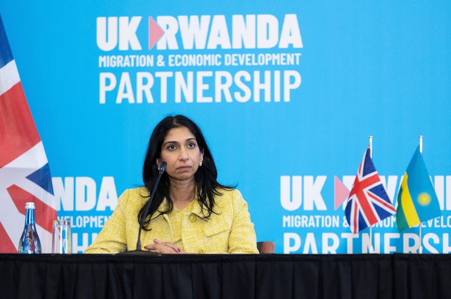 Suella Braverman sitting at a table in front of a blue wall that reads UK Rwanda migration and economic development partnership