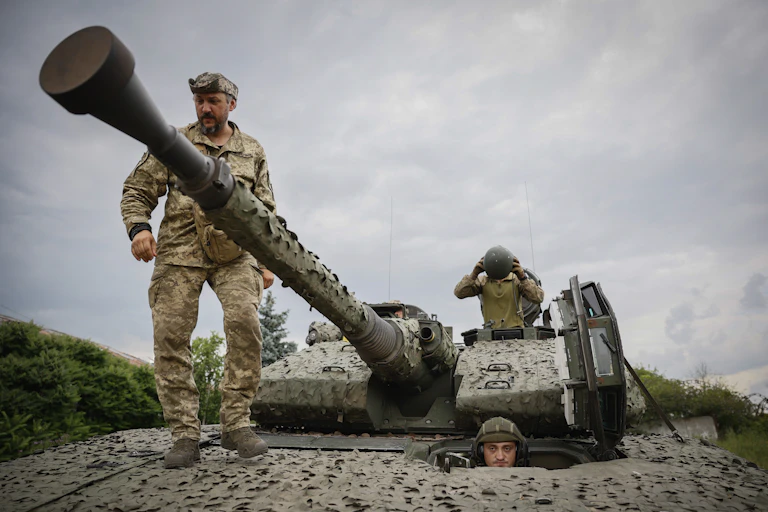 Three soldiers are on a military vehicle.