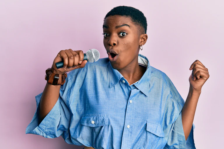 Woman in denim shirt with microphone singing.