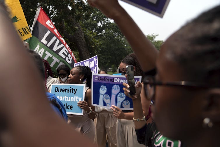 Protestors holding posters saying, 'Black Lives Matter' and 'Defend Diversity.'