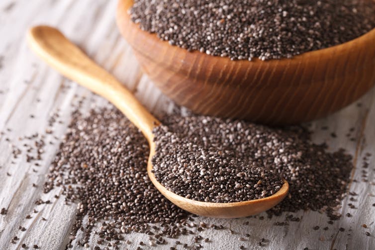 Chia seeds in a bowl, in a spoon, spilling onto surface