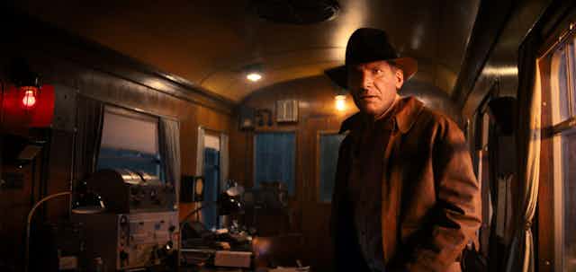 Harrison Ford as Indian Jones in the final film of the series standing in a 1940s train carriage.