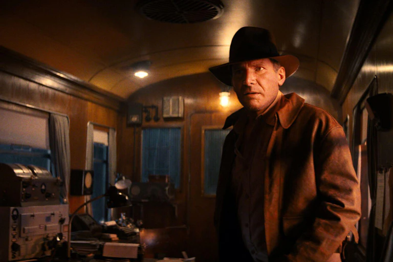 Harrison Ford as Indian Jones in the final film of the series standing in a 1940s train carriage.