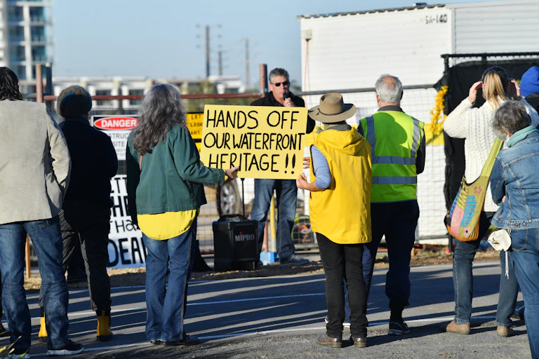 a sign reads 'Hands off our waterfront heritage' at a protest against a heritage building being redeveloped for housing