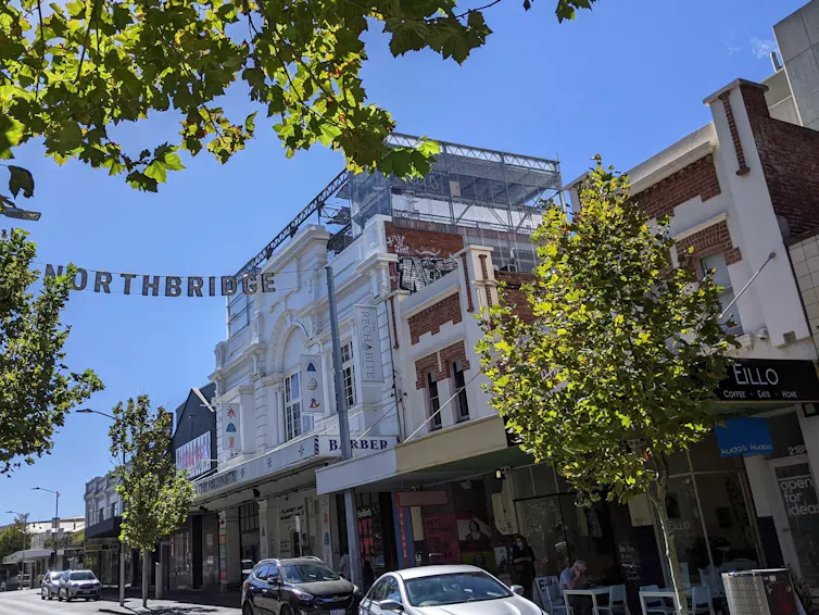 A new development rises behind a street of heritage building facades.