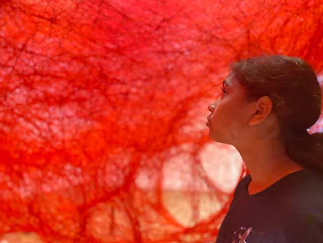 A student looks at a large red artwork.