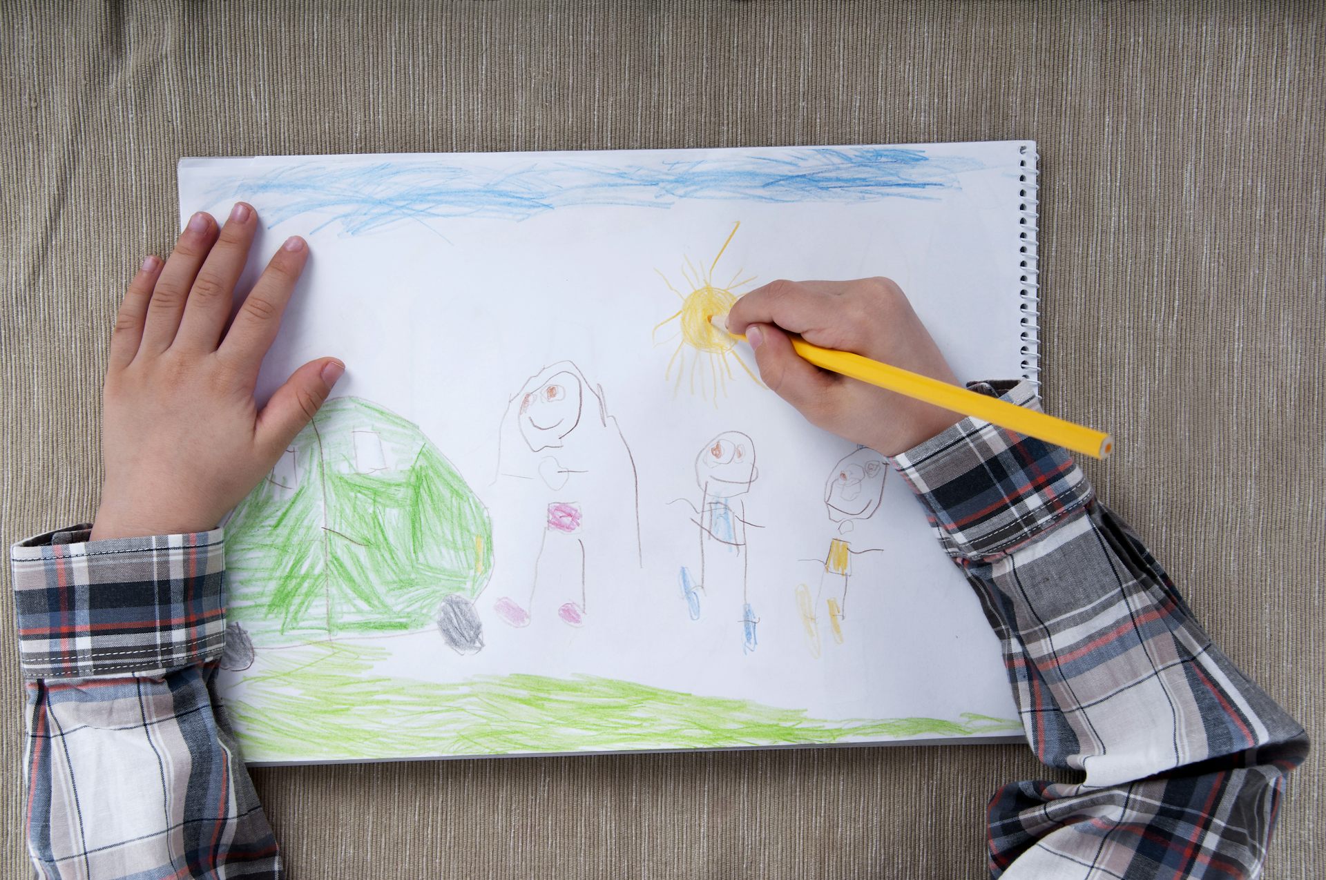 An overhead shot of a child drawing a picture.