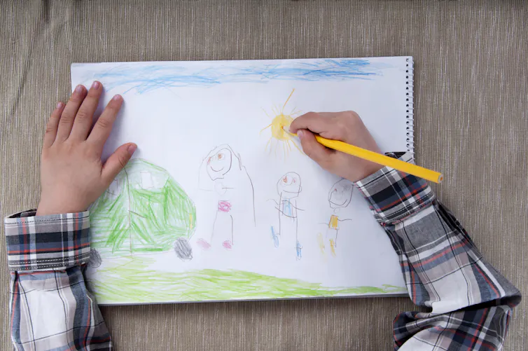 An overhead shot of a child drawing a picture.