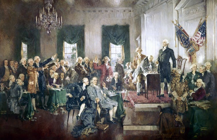 A painting depicts men dressed in old fashioned clothing in a large room crowded around some men on a raised platform.