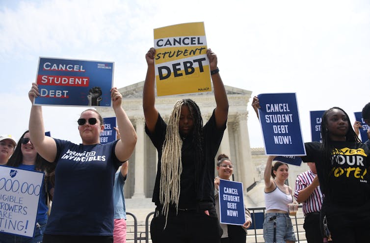 protestors standing with signs in support of debt cancellation