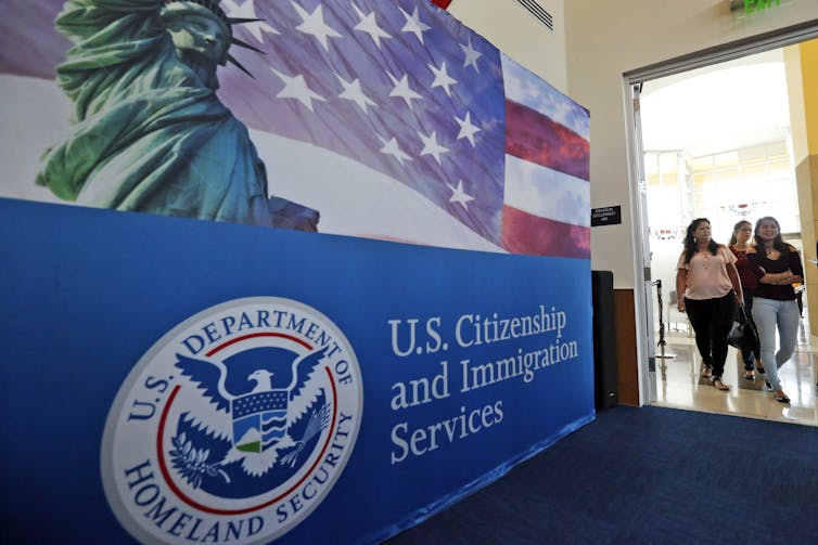 People enter a doorway before a U.S. Citizen and Immigration Services sign