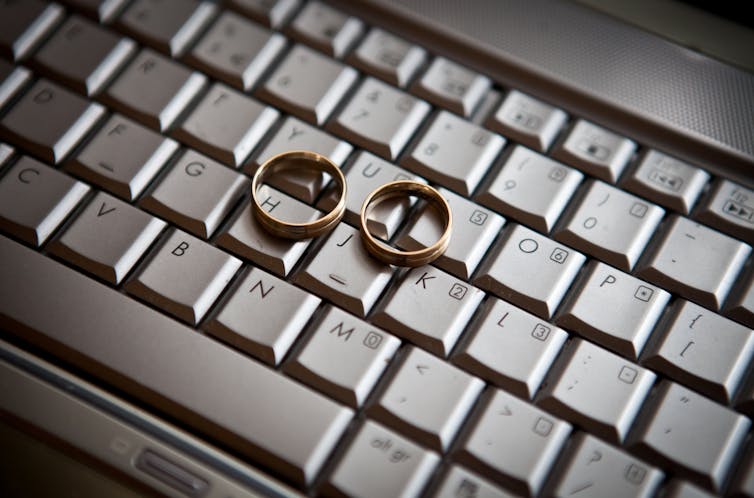 A computer keybord with two wedding rings sitting atop the keys