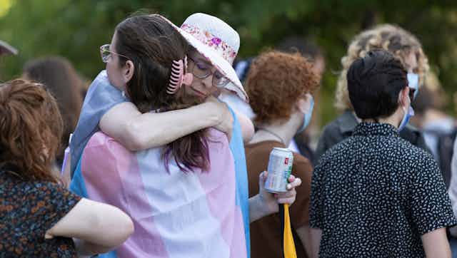 Picture of people embracing at an event, some in the crowd wearing face masks. 