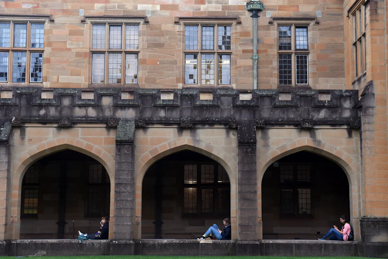 Three students sit in the quadrangle at Sydney University.
