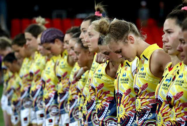 women in sporting uniforms bow heads