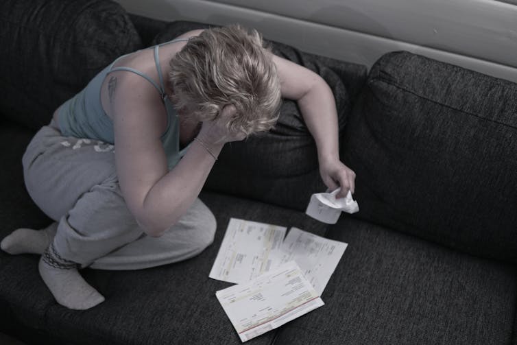 Woman sitting on floor with bills scattered around her