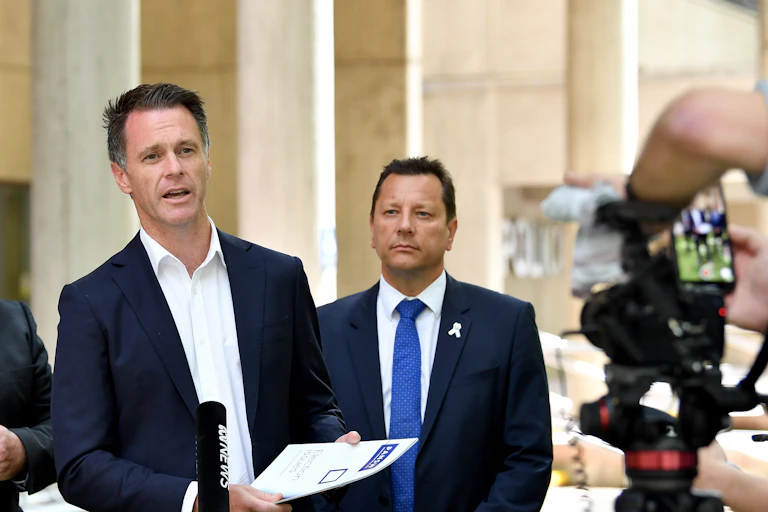 Two men stand in front of news media to make an announcement