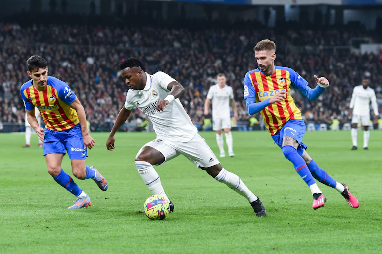 Three footballers mid-play.
