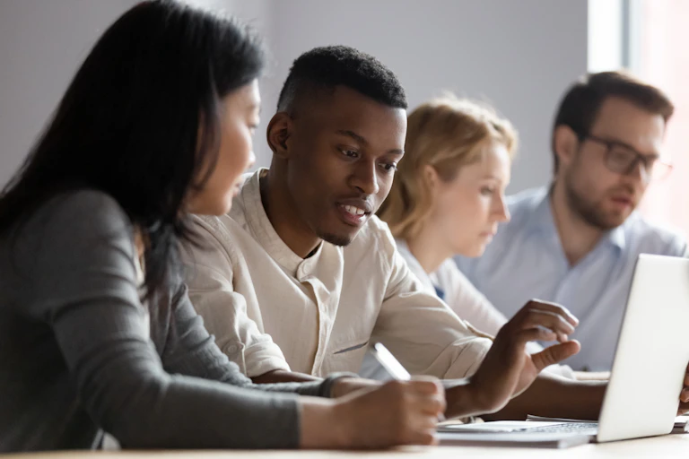 Group of professionals of different ages looking at laptop