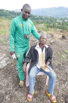 Two black men posing for the camera. One has a camera around his neck.