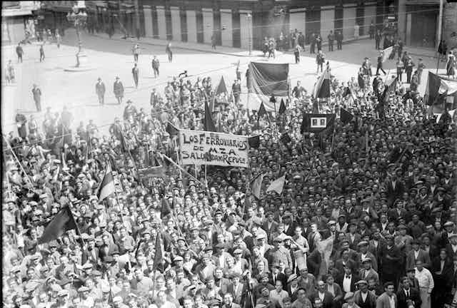 Fotografía en blanco y negro de una multitud con pancartas y banderas republicanas españolas,