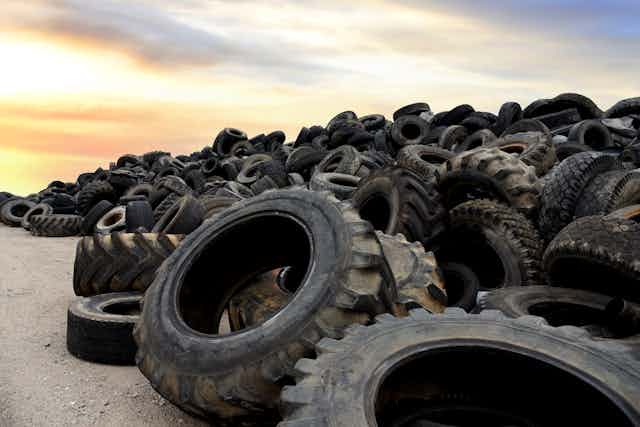 A pile of large rubber tyres in a rubbish heap.